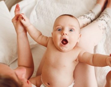 Cute baby showing moro reflex with arms and legs outstreched
